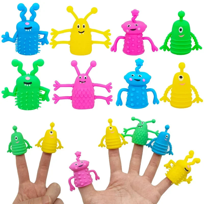A hand displays five colorful monster finger toppers made of plastic, including blue, yellow, green, and pink varieties.