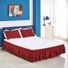 A bed with a red ruffled skirt covering the bottom of the mattress in a blue and white room.