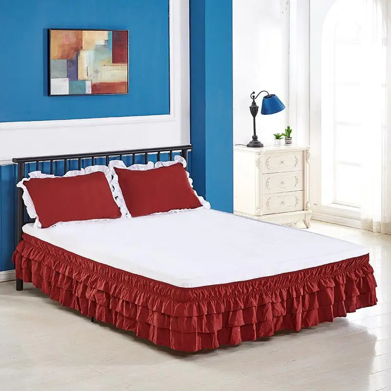 A bed with a red ruffled skirt covering the bottom of the mattress in a blue and white room.