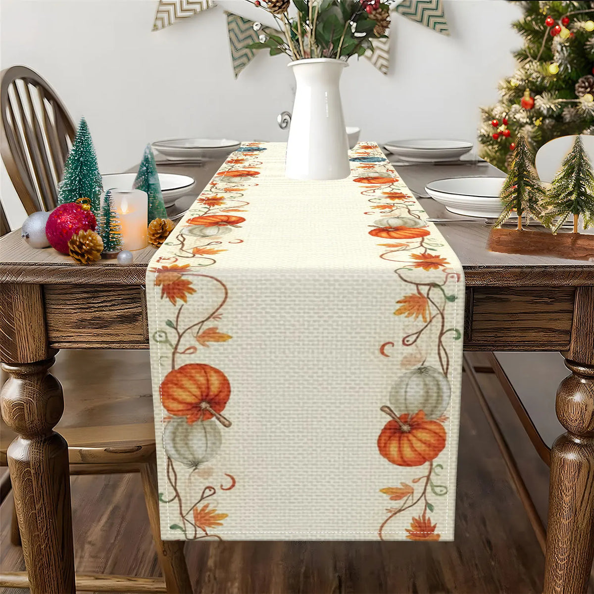 A beige table runner decorated with orange pumpkins and autumn leaves on a wooden table.