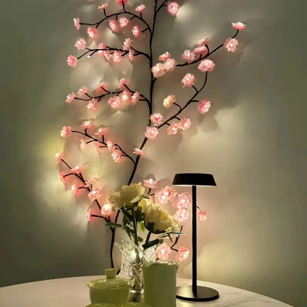 A decorative lamp featuring a branch of pink cherry blossoms with dimmable LED lights displayed on a white surface.