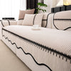 A beige striped chenille sofa cover with a black pleated hem displayed on a white sofa.