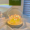 A handcrafted tulip LED night light with yellow flowers sits on a wooden base inside a clear glass dome.