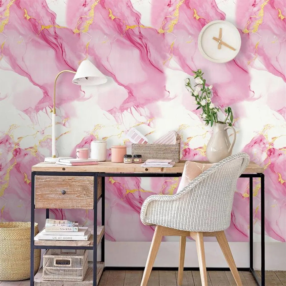 A desk setup featuring a pink marble pattern wall, a white lamp, and various stationery items.