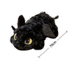 A black soft plush dragon toy resembling a Night Fury with yellow eyes and a wing, shown from above.