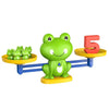 A green frog toy is balanced on a yellow bar, next to a red number 5 block.