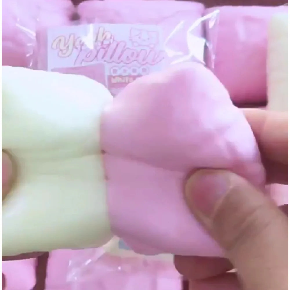 Une main tient un oreiller anti-stress rose et en forme de chat.