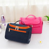 A pink hanging makeup bag is displayed next to a dark blue zippered pouch on a white surface.