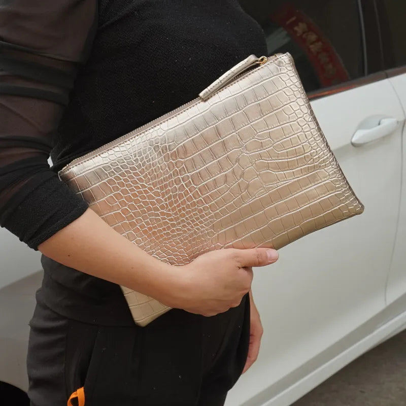 A person holds a beige crocodile-embossed PU leather envelope clutch against a white car door.