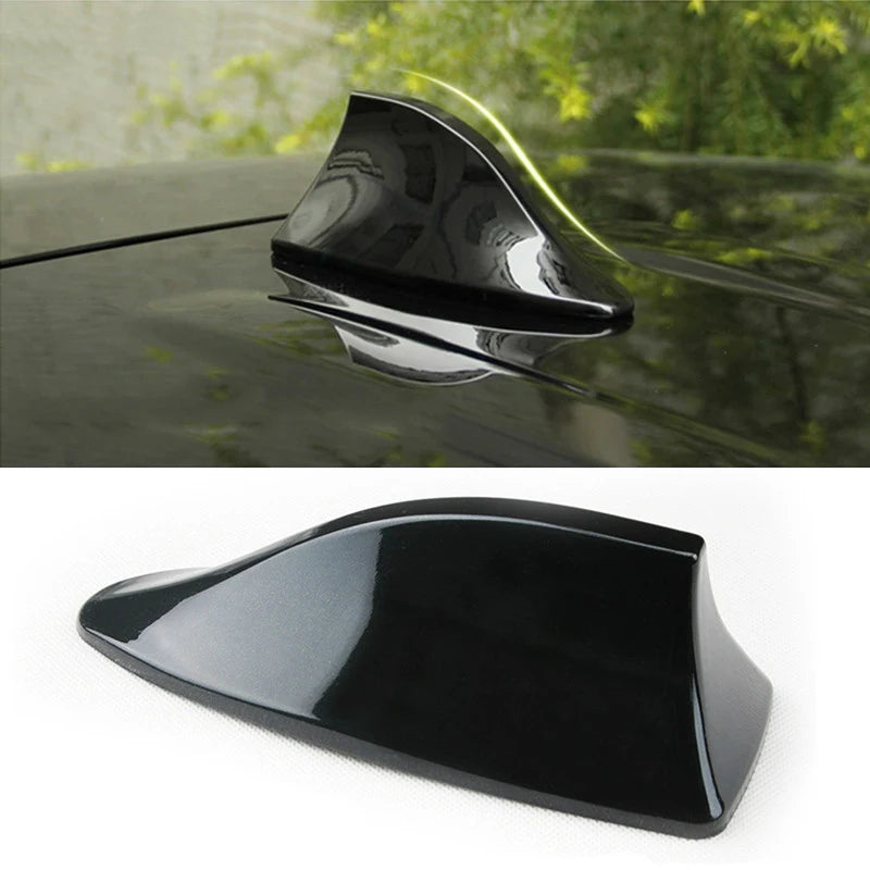 A black car shark fin antenna cover is shown in a close-up view against a dark car surface.