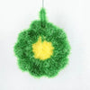 A bright green, fluffy dish sponge with a yellow center hanging from a string.