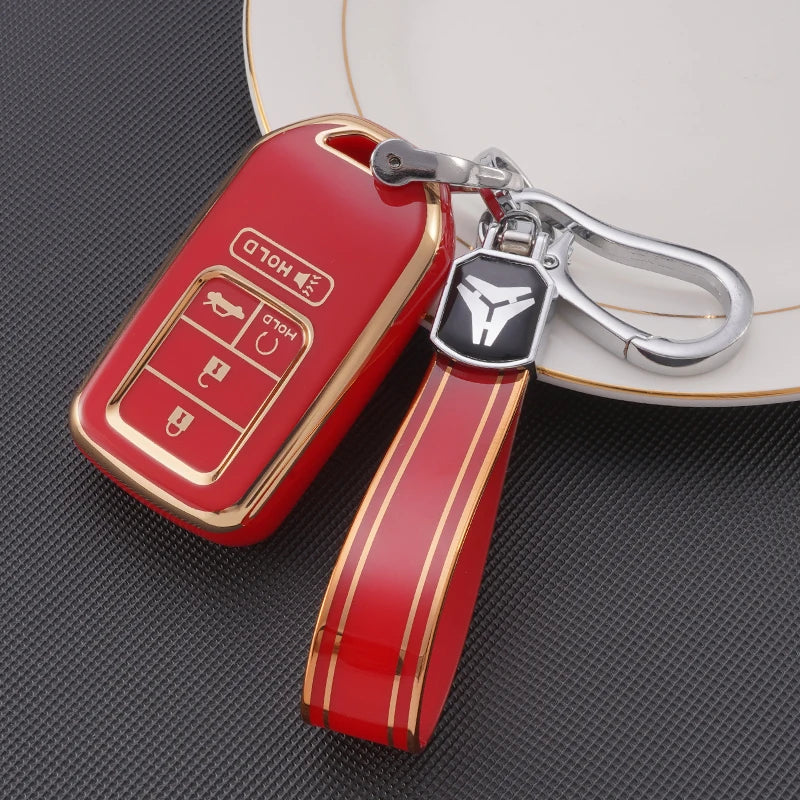 A red TPU protective key case with a silver keychain attached, resting on a dark surface.