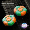 A glowing fidget spinner in orange and green colors resting on a black laptop keyboard.
