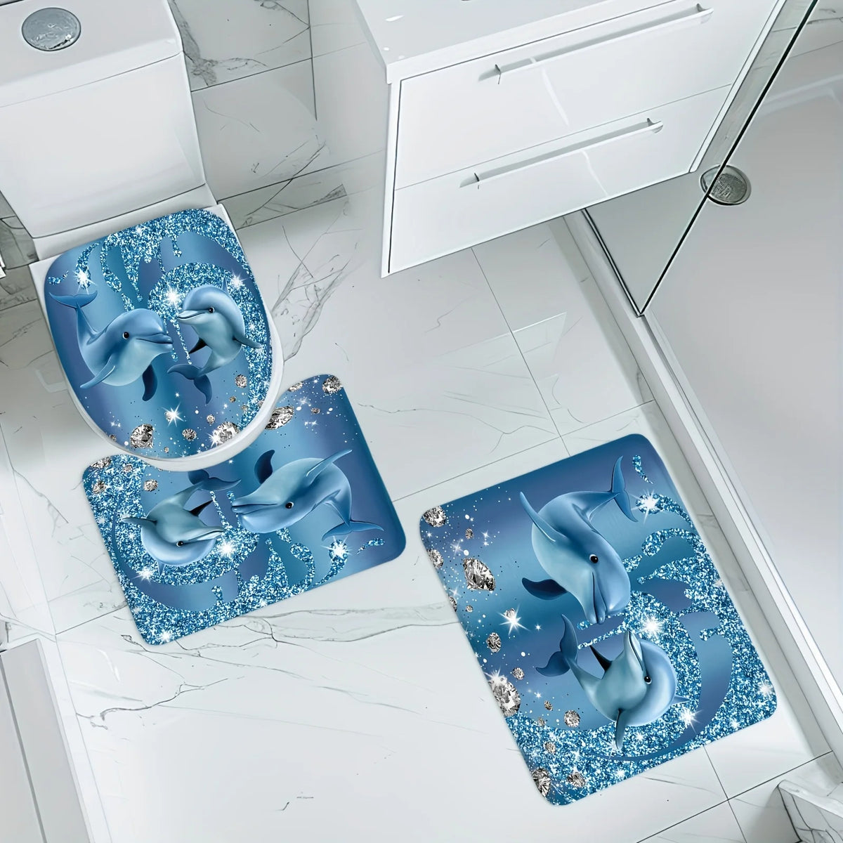 A set of three blue dolphin-themed bathroom mats featuring sparkling designs on a white marble floor.