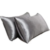 Un par de fundas de almohada de satén de seda gris, dobladas y exhibidas.