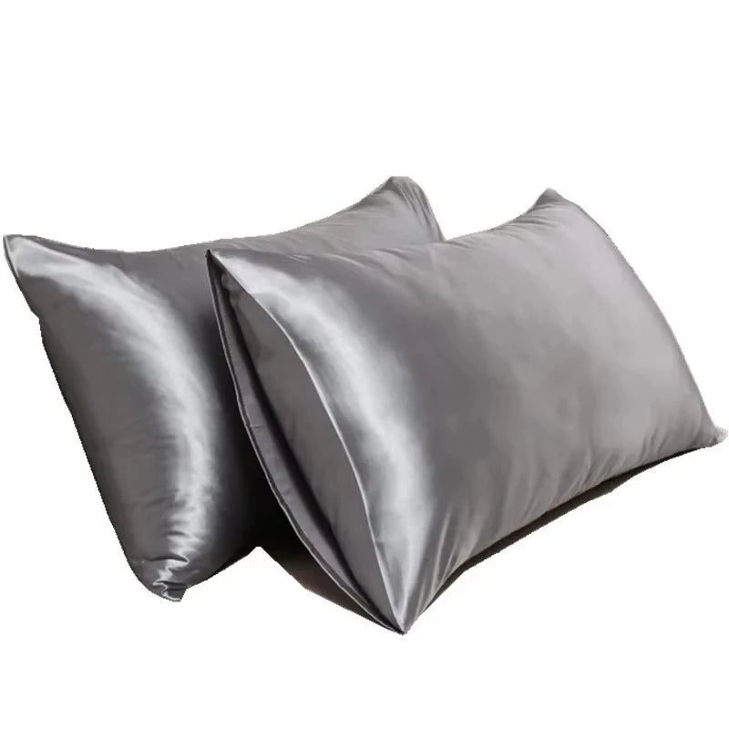 Un par de fundas de almohada de satén de seda gris, dobladas y exhibidas.