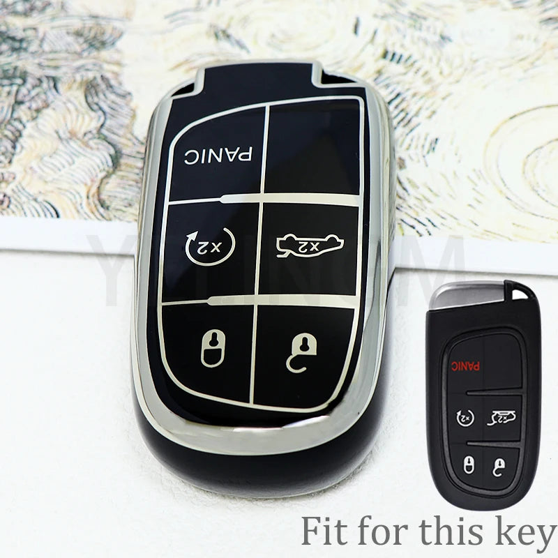 A black durable TPU car key fob cover with panic and unlock buttons displayed on a white surface.