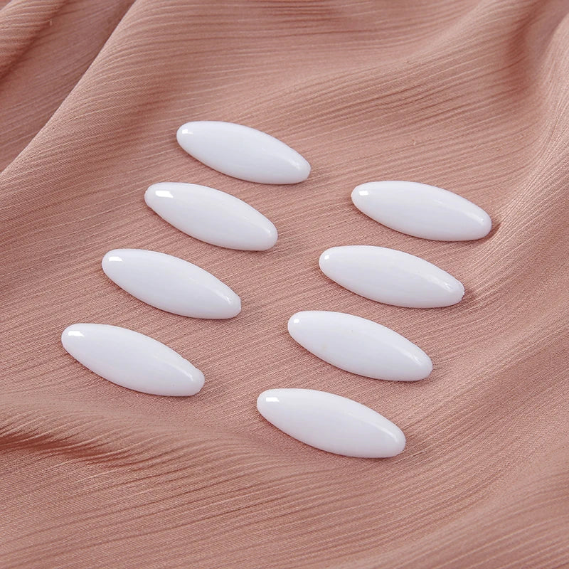 Eight oval white scarf pins arranged on a soft pink fabric.