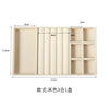 A light beige velvet jewelry organizer tray with three detachable compartments.