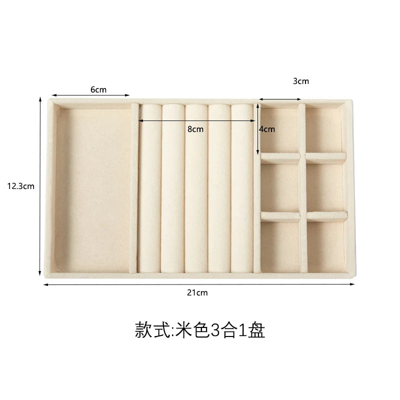 A light beige velvet jewelry organizer tray with three detachable compartments.