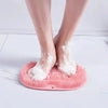 A pair of bare feet resting on a pink silicone exfoliating shower mat with bristles.