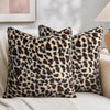 A close-up of three plush velvet leopard print pillows resting on a light-colored sofa.
