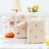 A pair of beige mini waterproof wet dry bags with gold sun designs are displayed on a white surface.