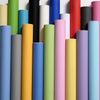 A vertical arrangement of colorful self-adhesive peel-and-stick wallpaper rolls in various shades of green, yellow, blue, pin