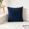 A dark blue corduroy pillowcase with a striped velvet design resting on a white surface.