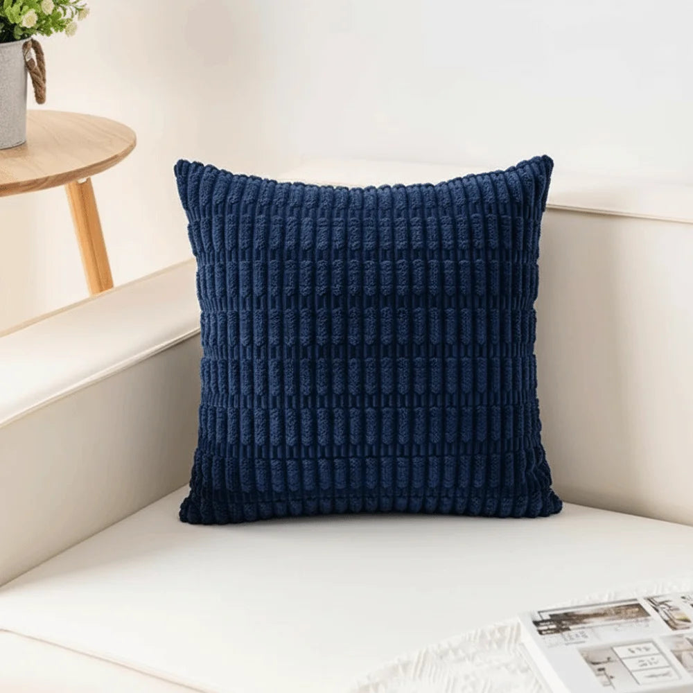 A dark blue corduroy pillowcase with a striped velvet design resting on a white surface.