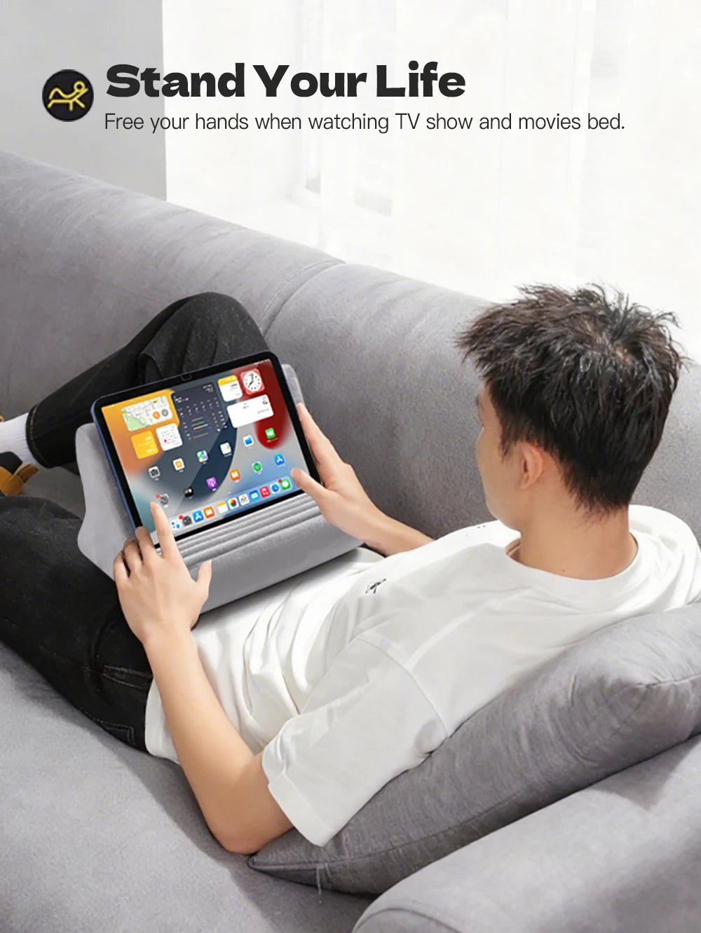 A person is relaxing on a couch watching TV with a tablet placed on an adjustable stand.