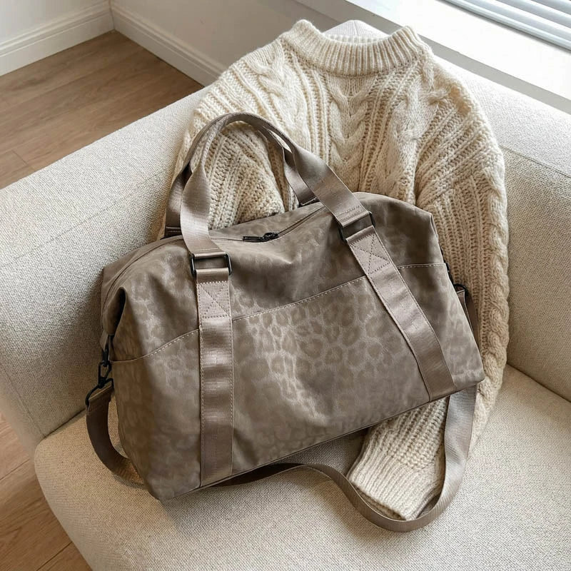 A tan leopard print duffle bag resting on a light-colored sofa.