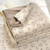 A stack of light beige cartoon pattern kids lightweight summer quilts lying on a white textured surface.