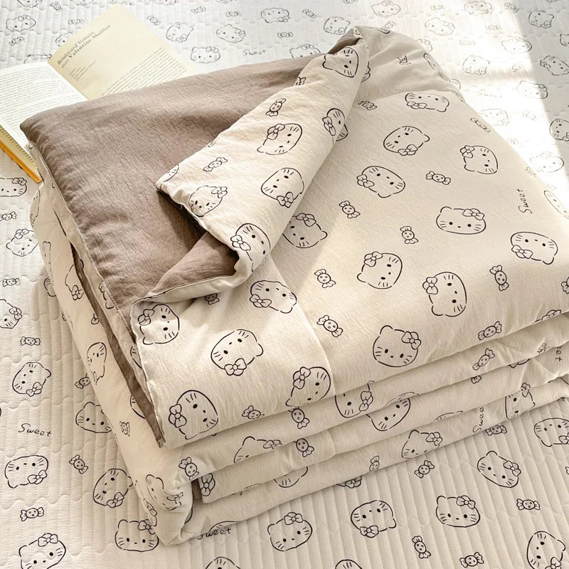 A stack of light beige cartoon pattern kids lightweight summer quilts lying on a white textured surface.