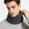 A man wearing a gray sweater and a dark gray knitted neck warmer scarf