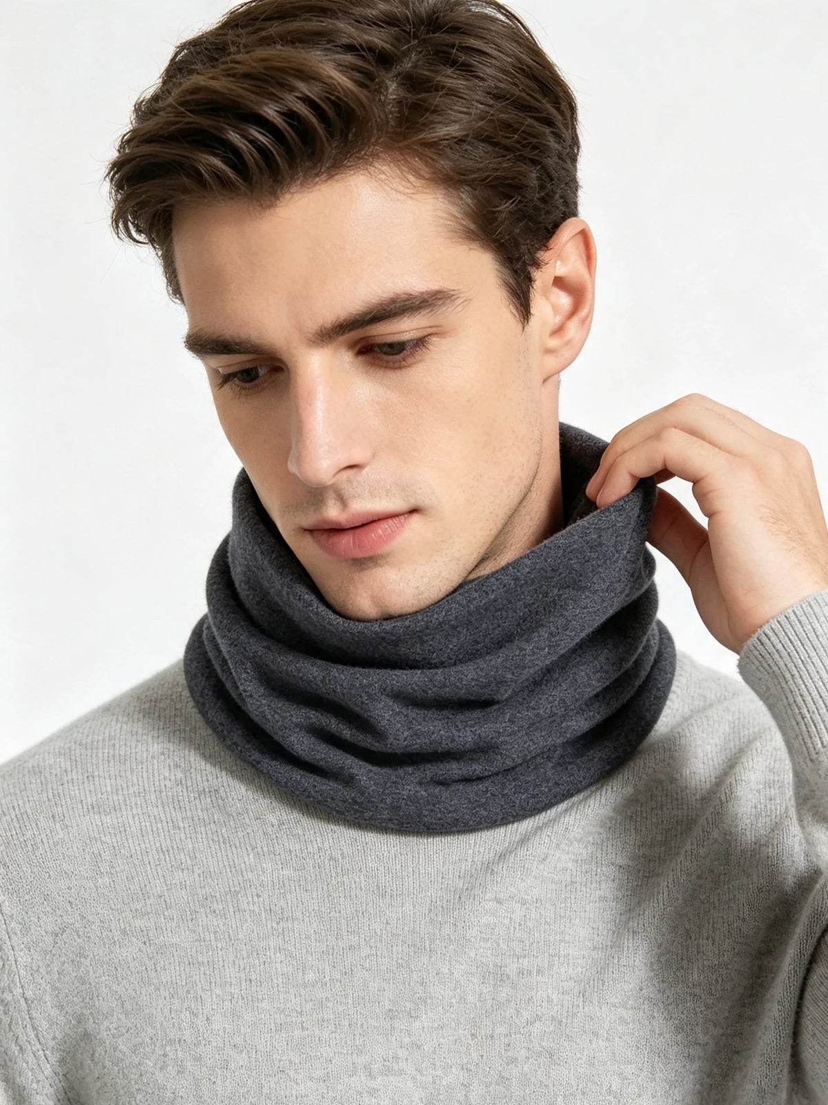 A man wearing a gray sweater and a dark gray knitted neck warmer scarf