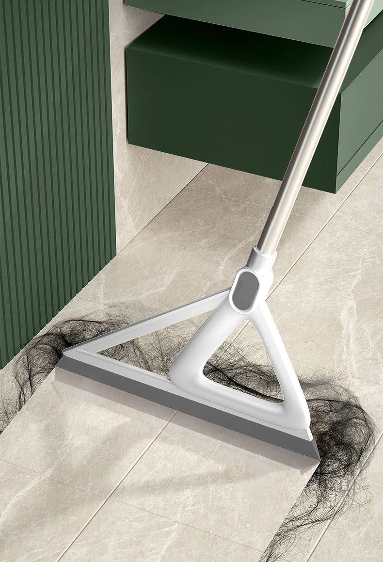 A white silicone squeegee broom is shown cleaning a light-colored floor next to a dark green cabinet.