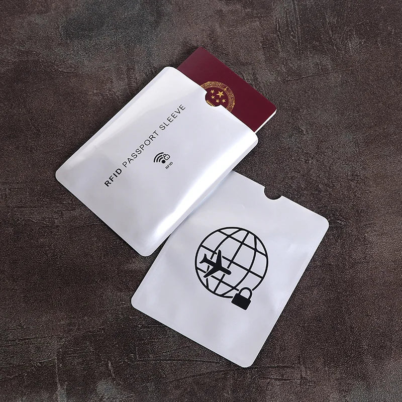 A white RFID passport sleeve is shown next to a maroon card, with another white sleeve lying below on a dark surface.