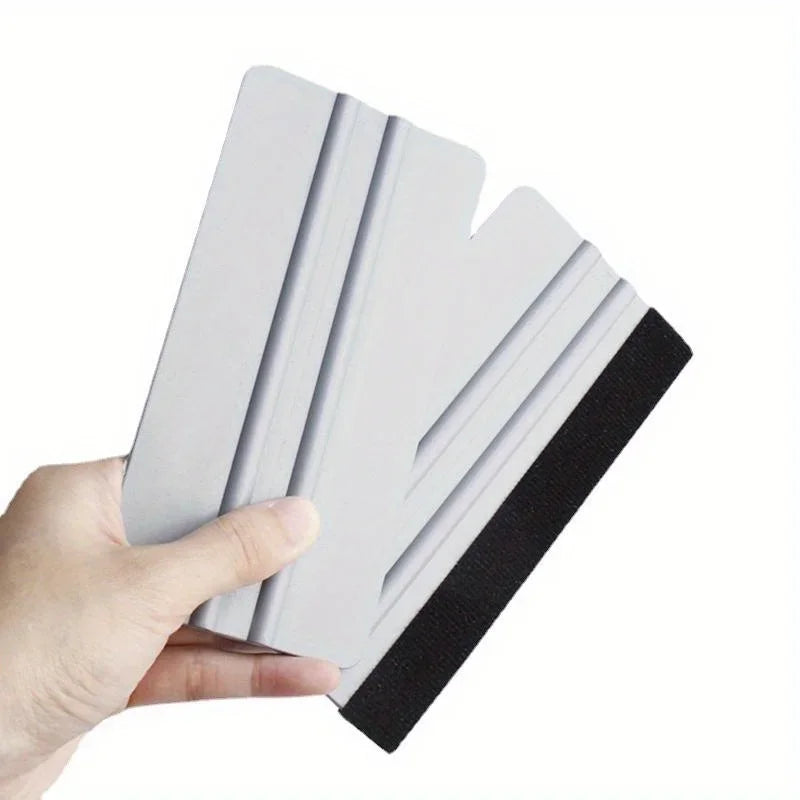 A hand holds a white scratch-free vinyl applicator tool with a black grip, showing its layered design.