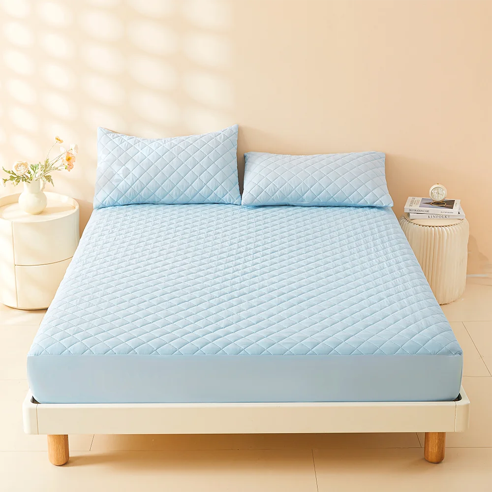 Hellblaue gesteppte Matratzenzugewand mit Kissen auf einem Bett bei Tageslicht.