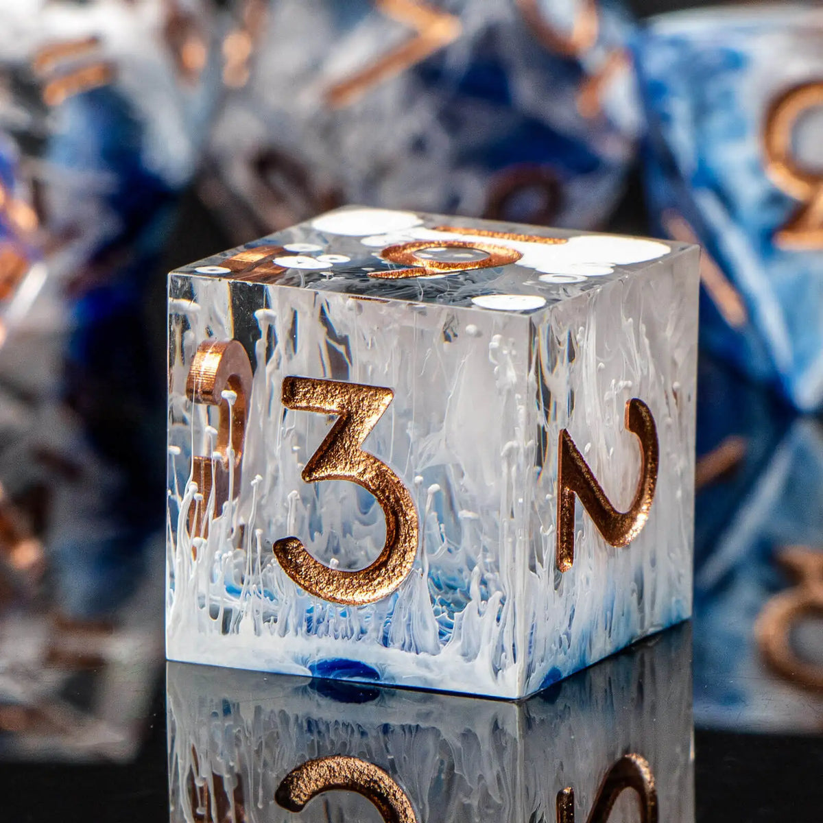 A close-up of a translucent white resin die with the number 3 and an N, resting on a reflective surface.