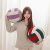 A young woman holds a purple and white striped simulation volleyball plush toy pillow.