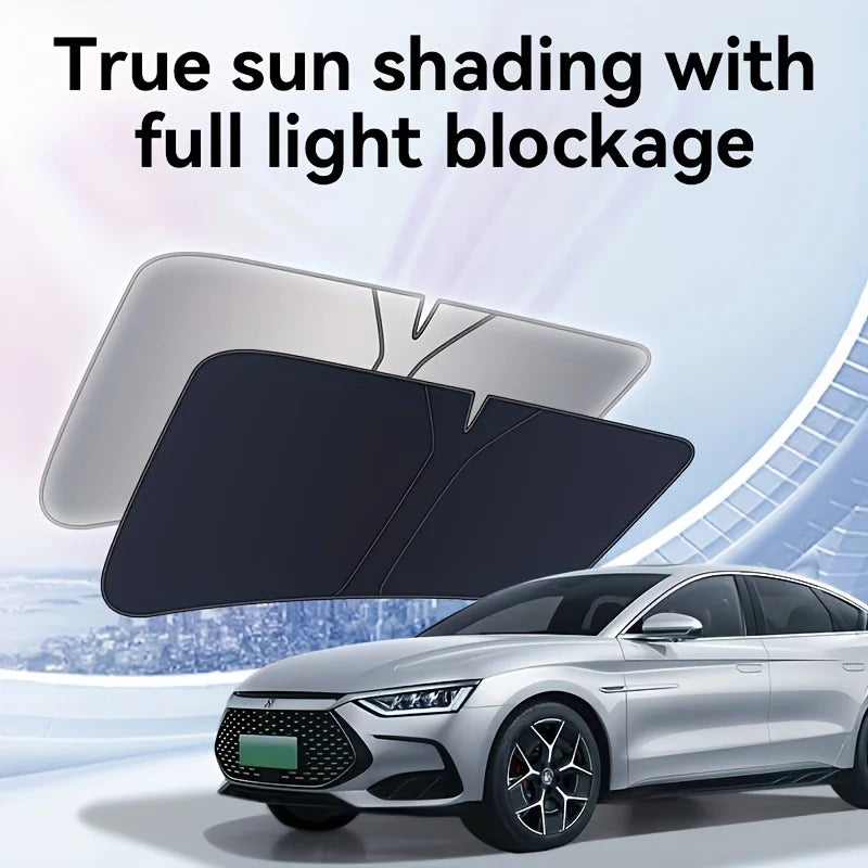 A black foldable car windshield sunshade is shown in use on a silver sedan.