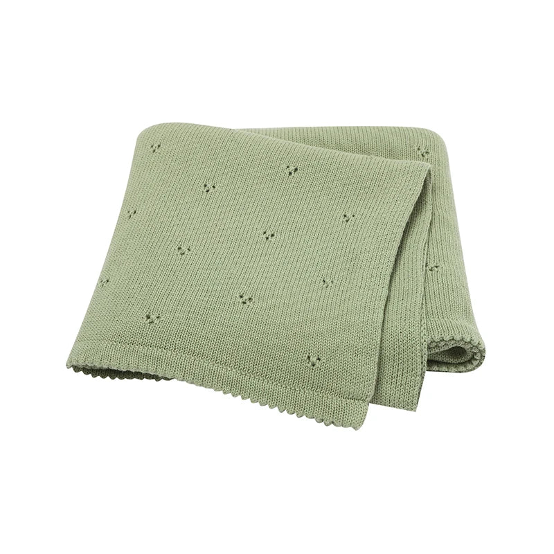 A light sage green knitted soft cotton baby blanket with small eyelet holes.