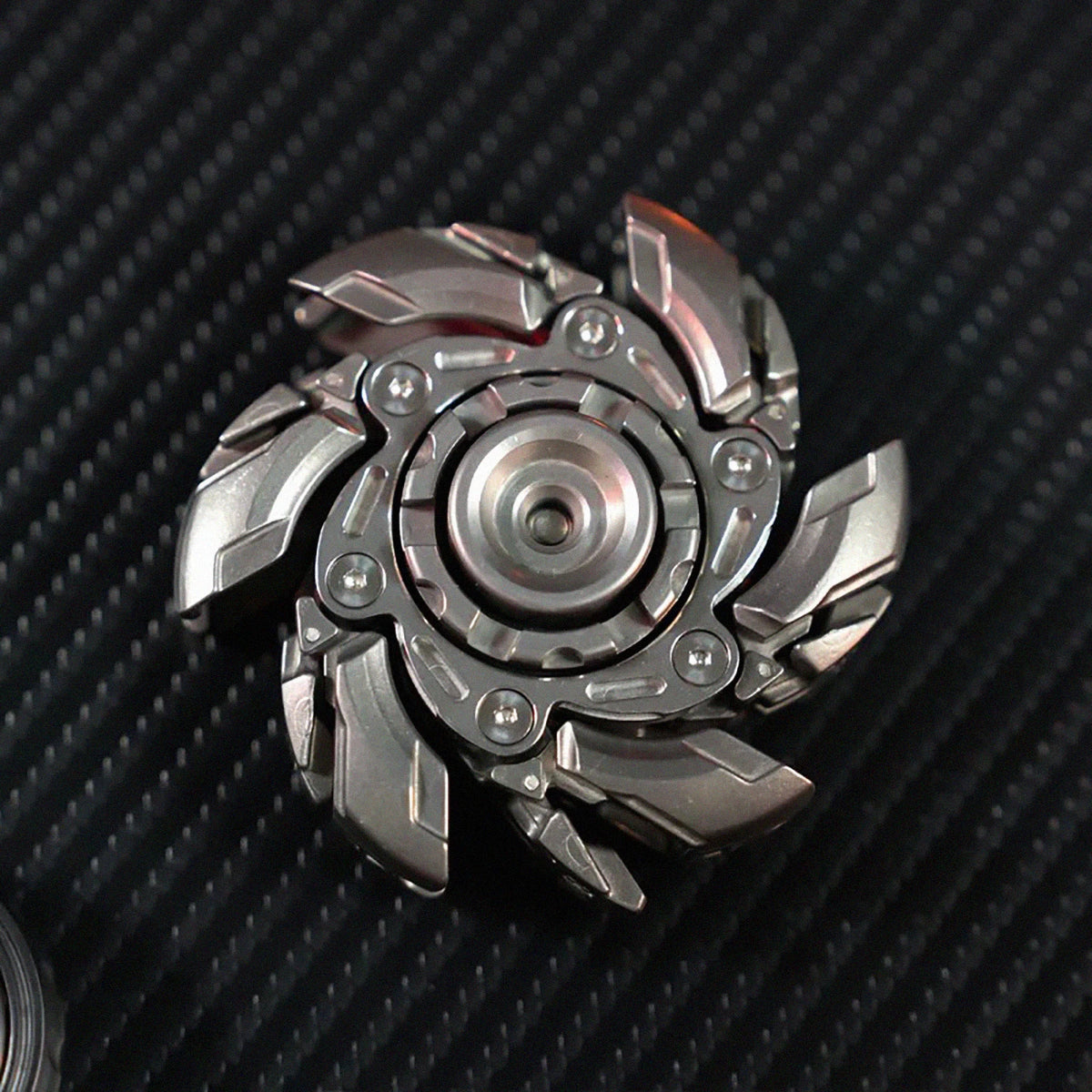 A metallic, multi-bladed fidget spinner with a central hub, shown against a dark background.