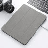 A gray Retro Marble iPad Pro 12.9 case with a pencil holder resting on a white desk next to a laptop and camera.