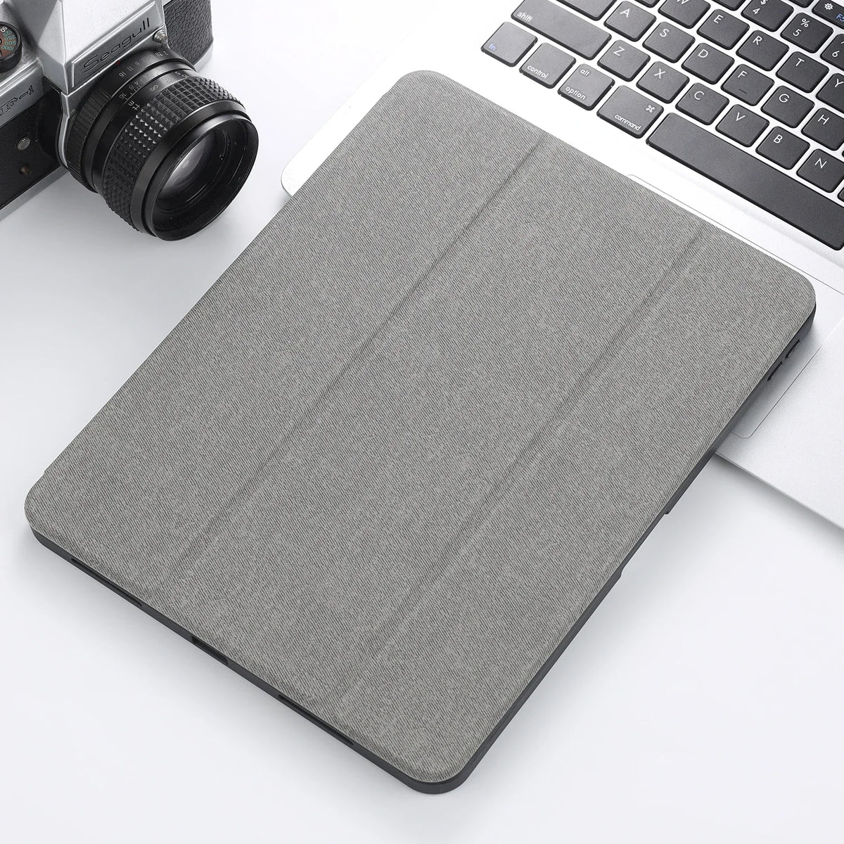A gray Retro Marble iPad Pro 12.9 case with a pencil holder resting on a white desk next to a laptop and camera.