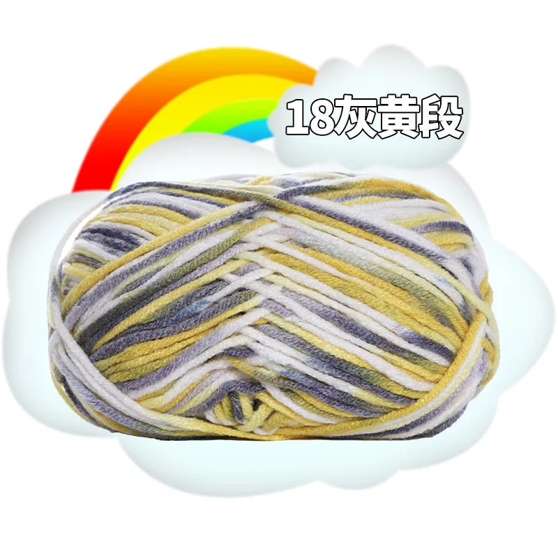 A ball of milk cotton blend yarn with stripes of yellow, gray, and white threads.