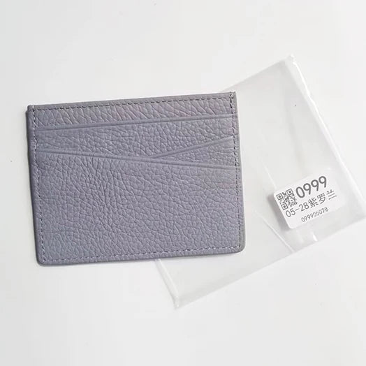 A gray genuine leather slim card holder wallet placed on a clear plastic background.