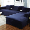 A dark navy blue plush velvet elastic sofa cover is shown on an L-shaped sectional sofa in a living room setting.